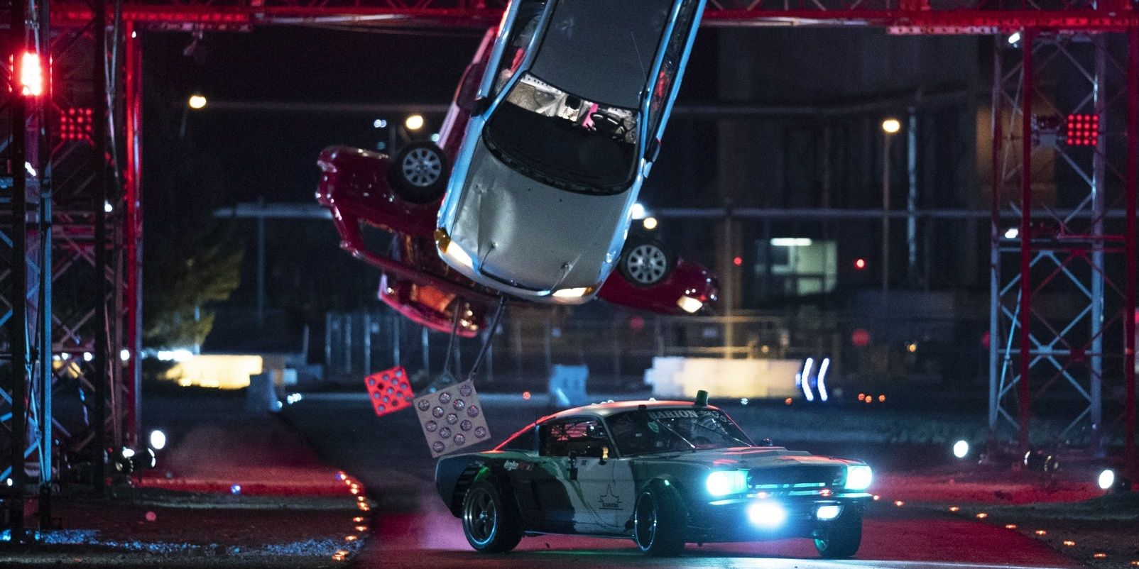 A car maneuvers through an obstacle course, which includes suspended cars, in Netflix's Hyperdrive