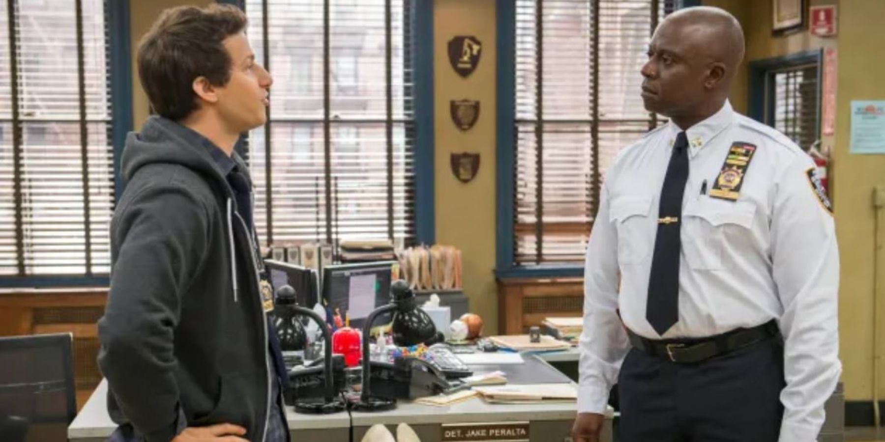 Jake and Holt standing facing each other in the precinct in Brooklyn Nine-Nine