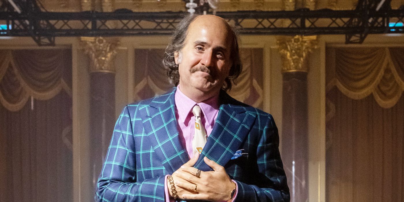 Paolo Gucci smiles while talking on a stage in House of Gucci.