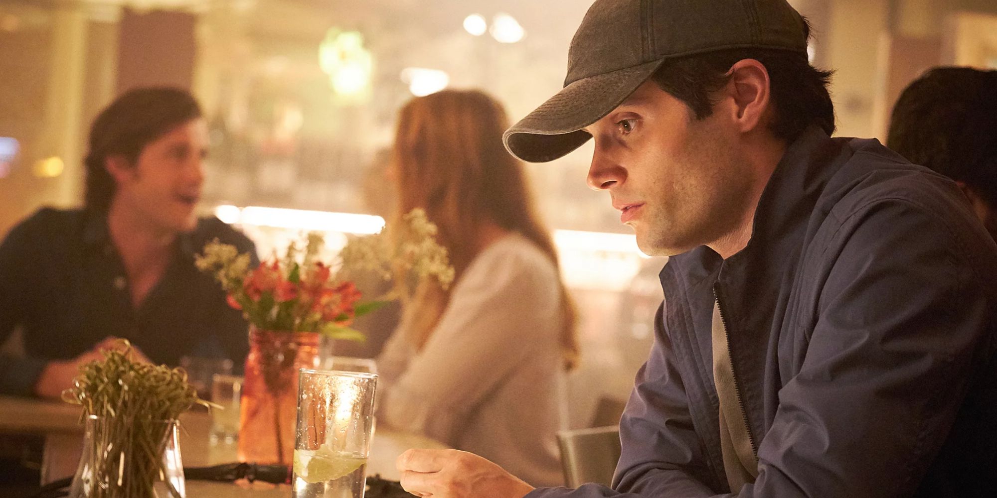 Joe sits at a table in Netflix's You.
