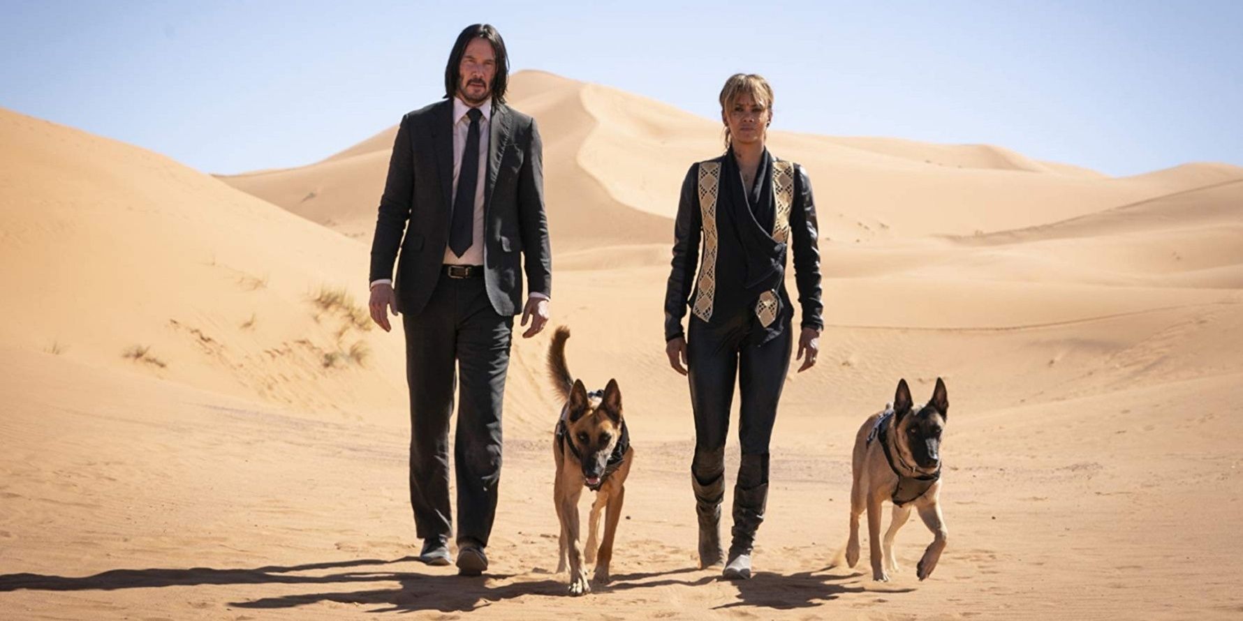 Keanu Reeves and Halle Berry walk through the desert with dogs in John Wick: Chapter 3 - Parabellum