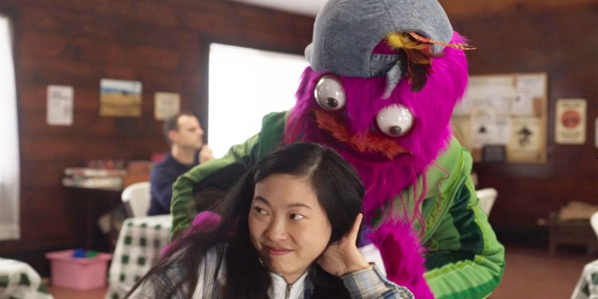 A purple costumed dinosaur tackles Nora in Nora from Queens.