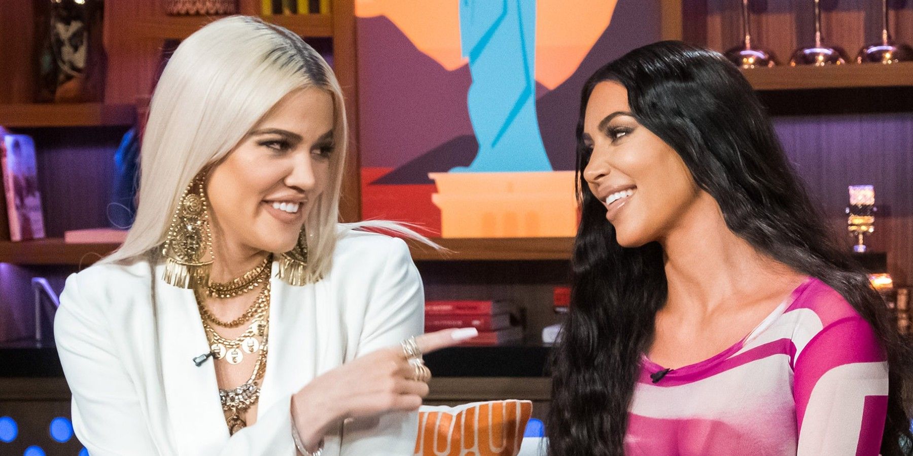 Kim and Khloe smiling as Khloe points a finger