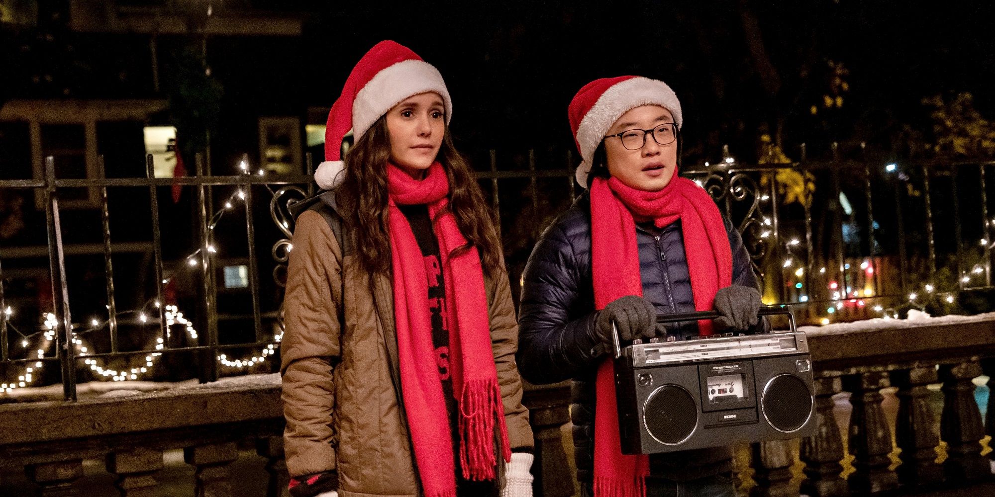 Nina Dobrev and Jimmy O. Yang with a boombox and in Santa hats in Love Hard