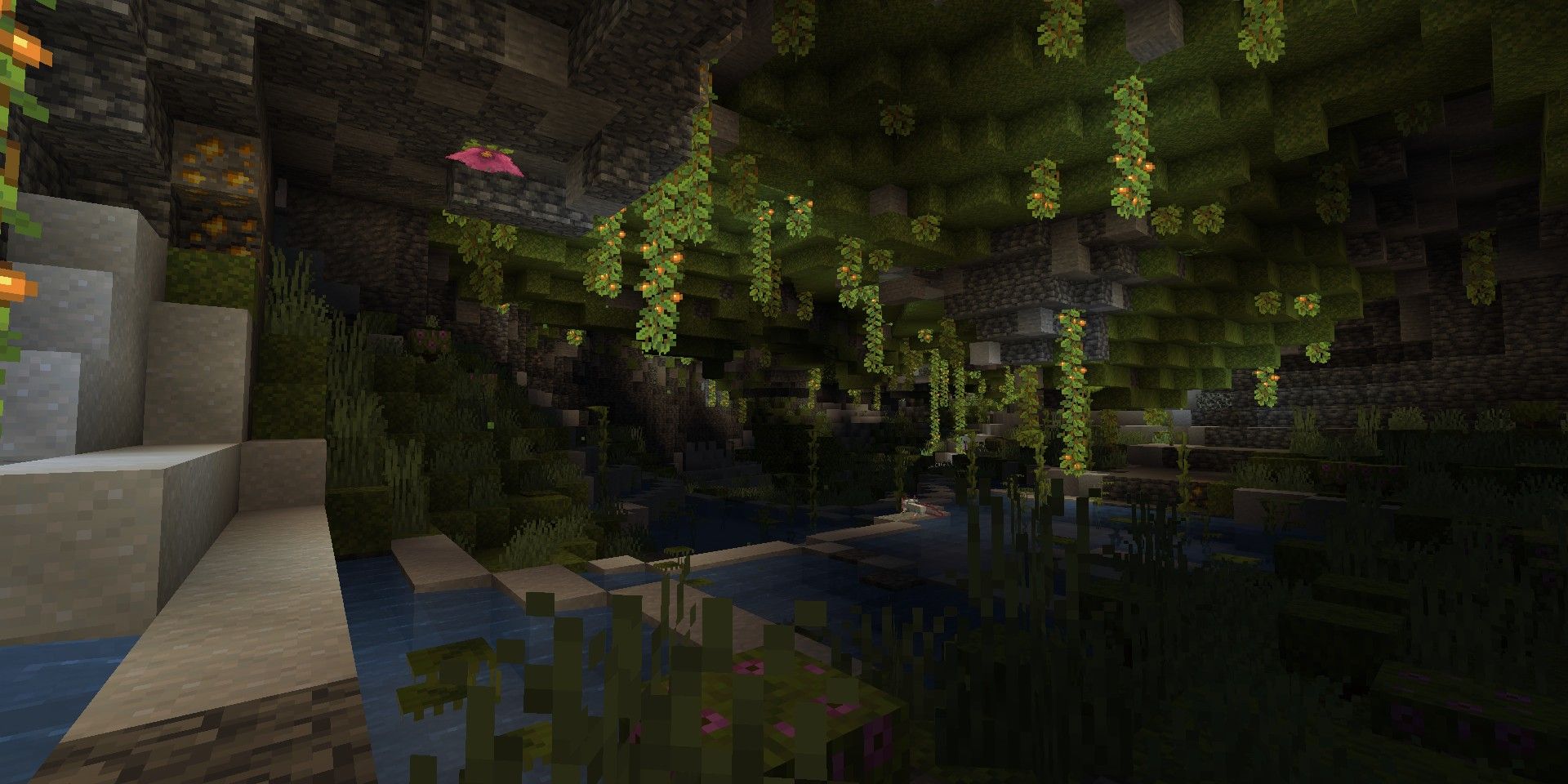 The inside of a lush cave in Minecraft, where moss hangs from the ceiling and flowers twinkle in the distance.