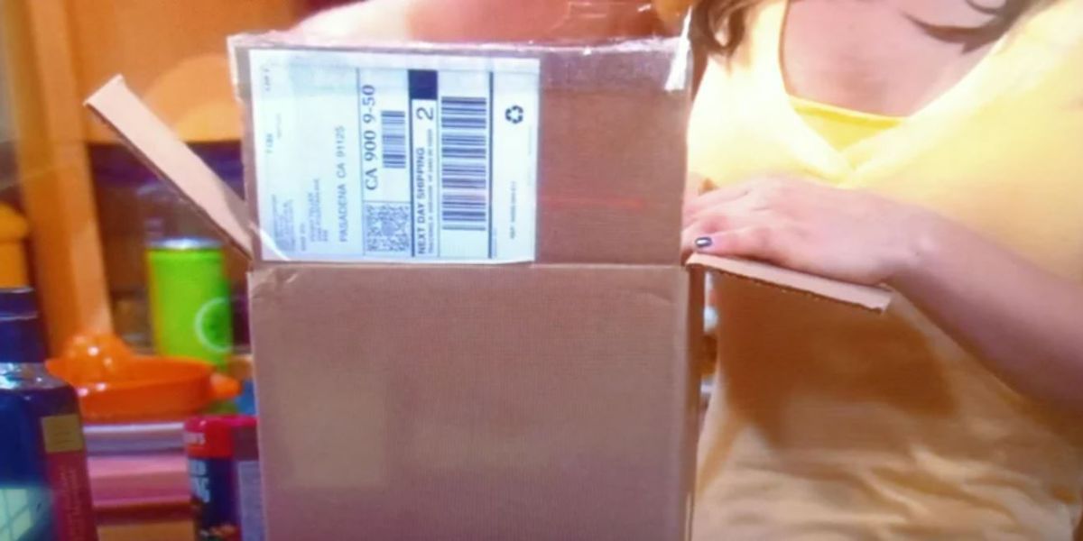 Cut off picture of Penny holding a package with a mailing label on it in TBBT