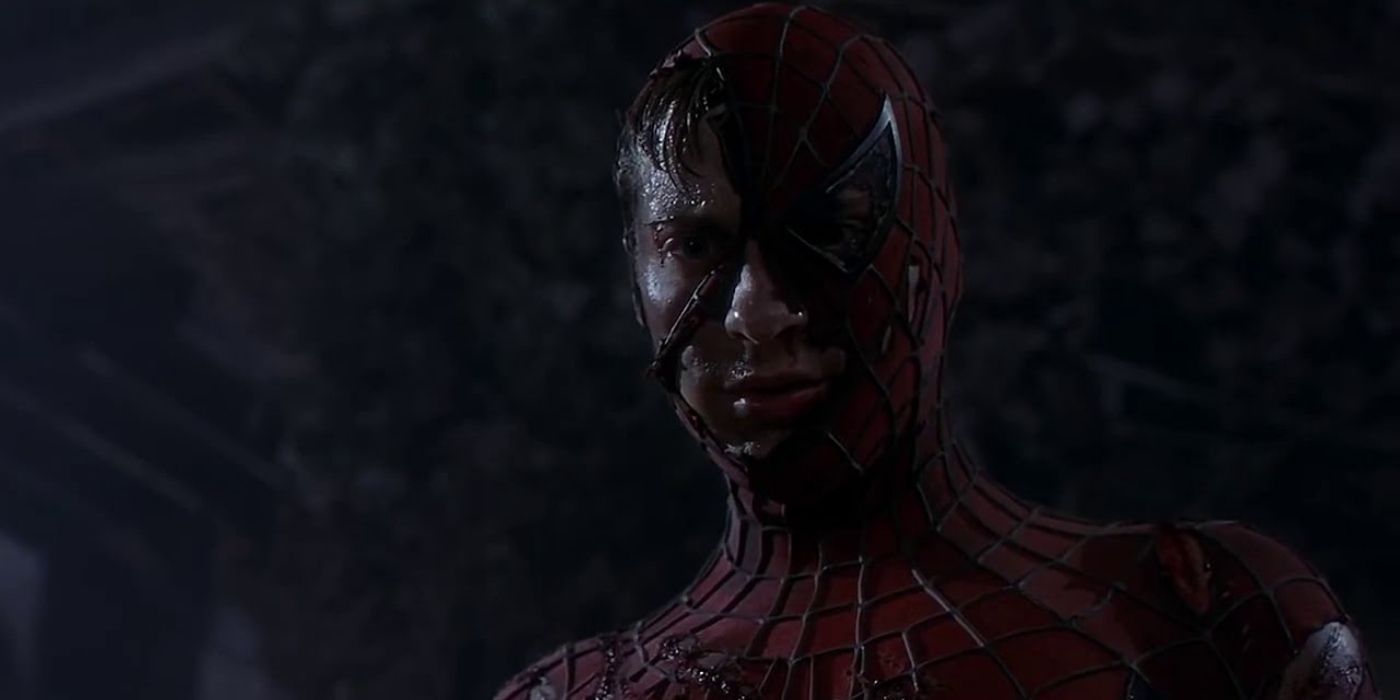 Spider-Man wearing a torn costume and looking down at someone in 2002's Spider-Man