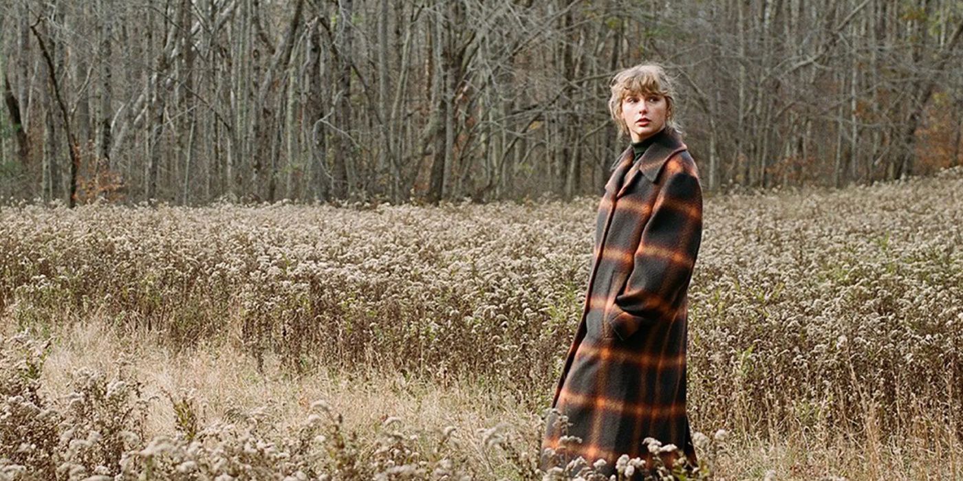 Taylor Swift walks in a field in a plaid coat