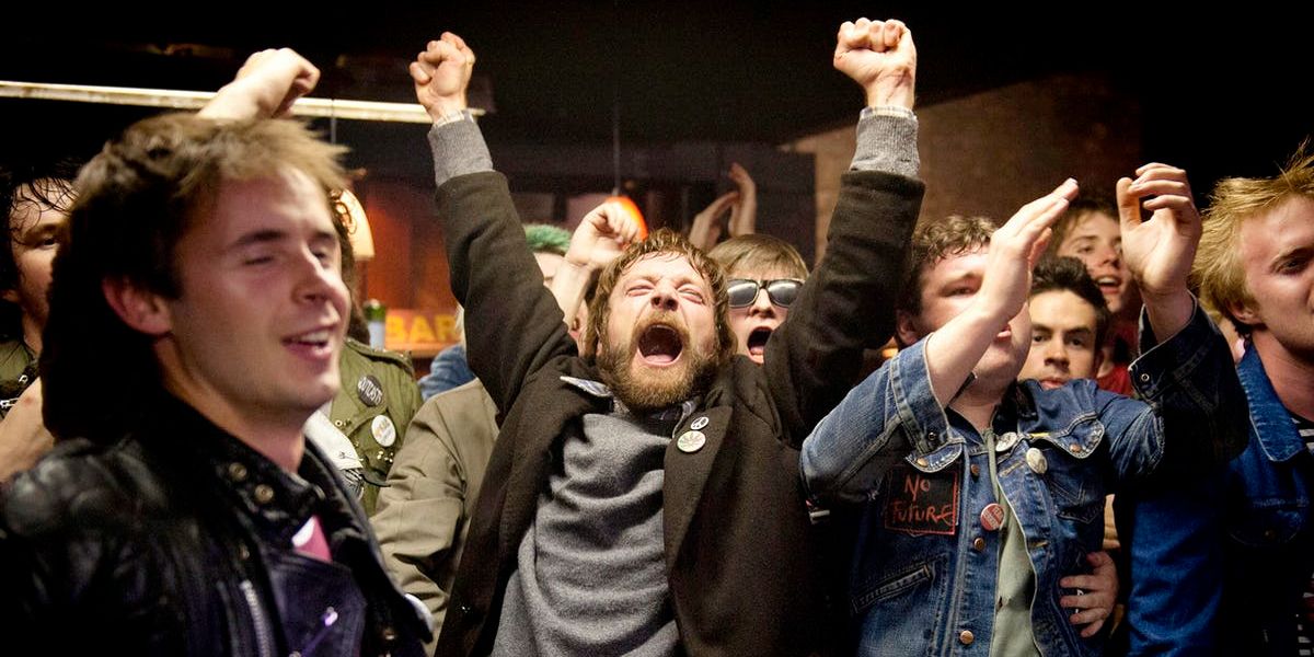 Terri Hooley (Richard Dormer) cheering in a crowded punk show in Good Vibrations