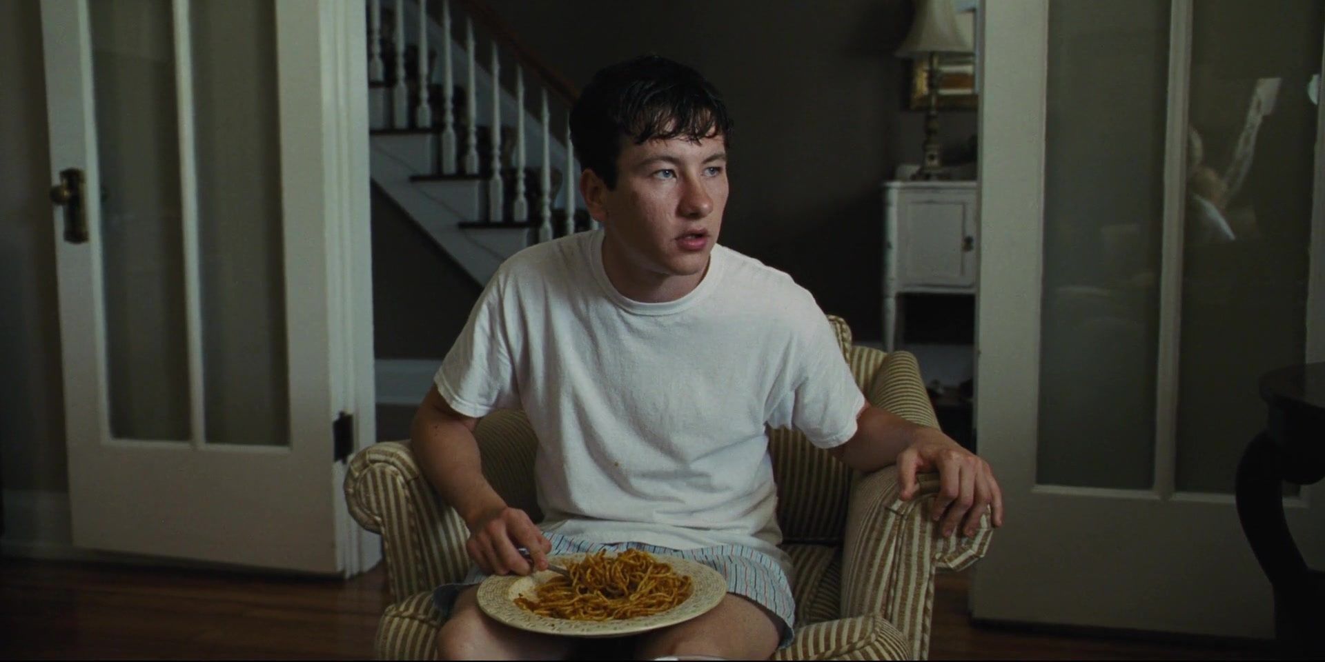 Barry Keoghan as Martin eats spaghetti with the plate on his lap in The Killing of a Sacred Deer