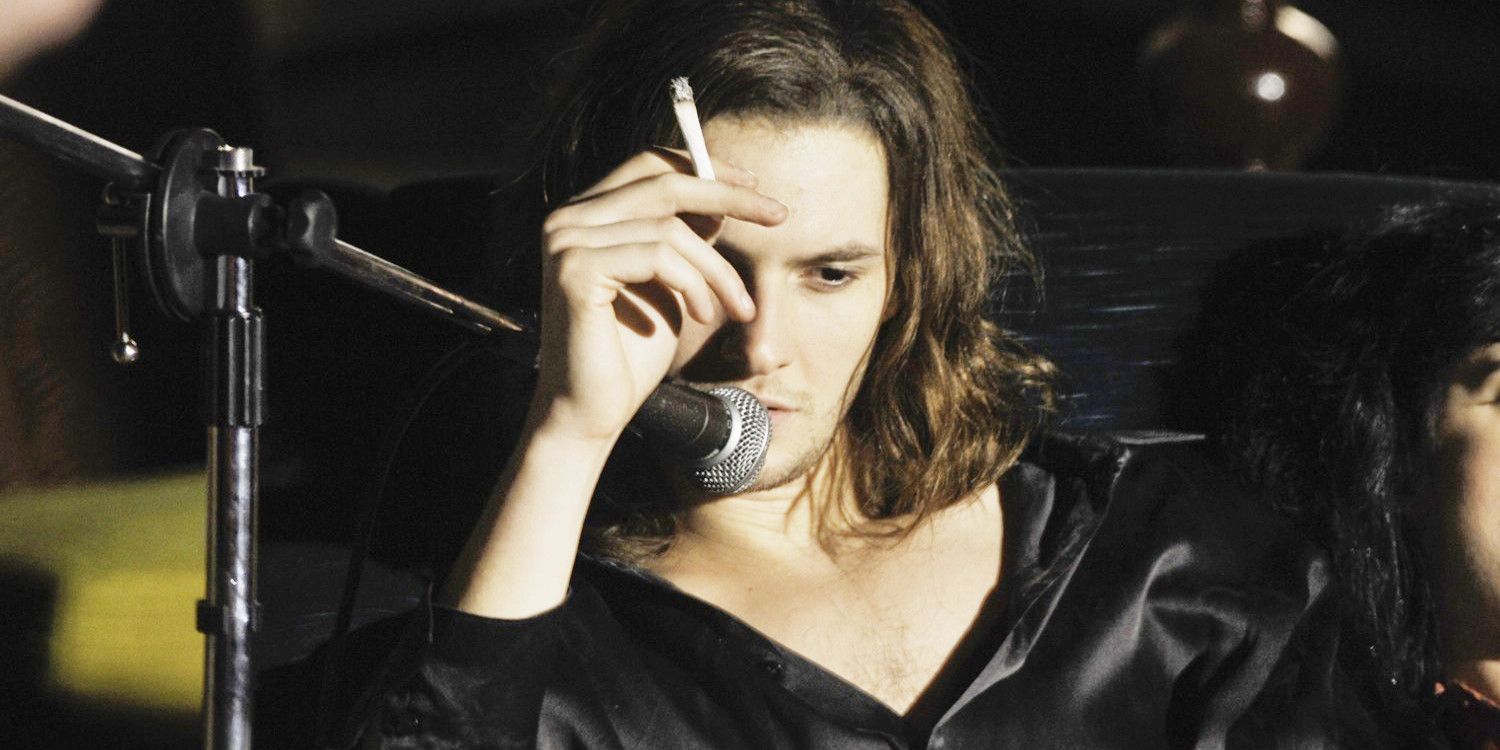 A man smokes a cigarette while speaking into a microphone in Killing Bono.