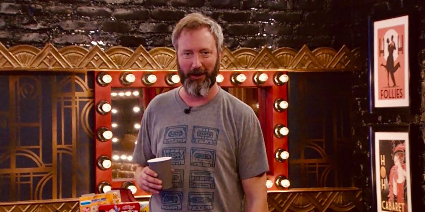 Tom Green from Celebrity Big Brother holding a cup of coffee and wearing a T-shirt with cassette tape images on the front.