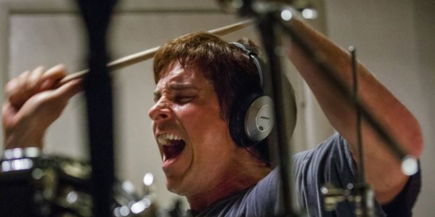 Christian Bale wearing headphones, screaming, and banging on drums in a scene from The Big Short.