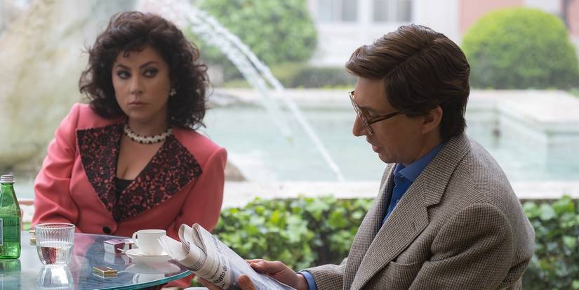Lady Gaga and Adam Driver as Patrizia and Maurizio at a table in House of Gucci