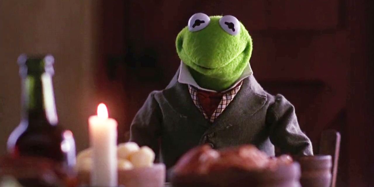 Kermit the Frog sits at a candle lit table in The Muppet Christmas Carol.