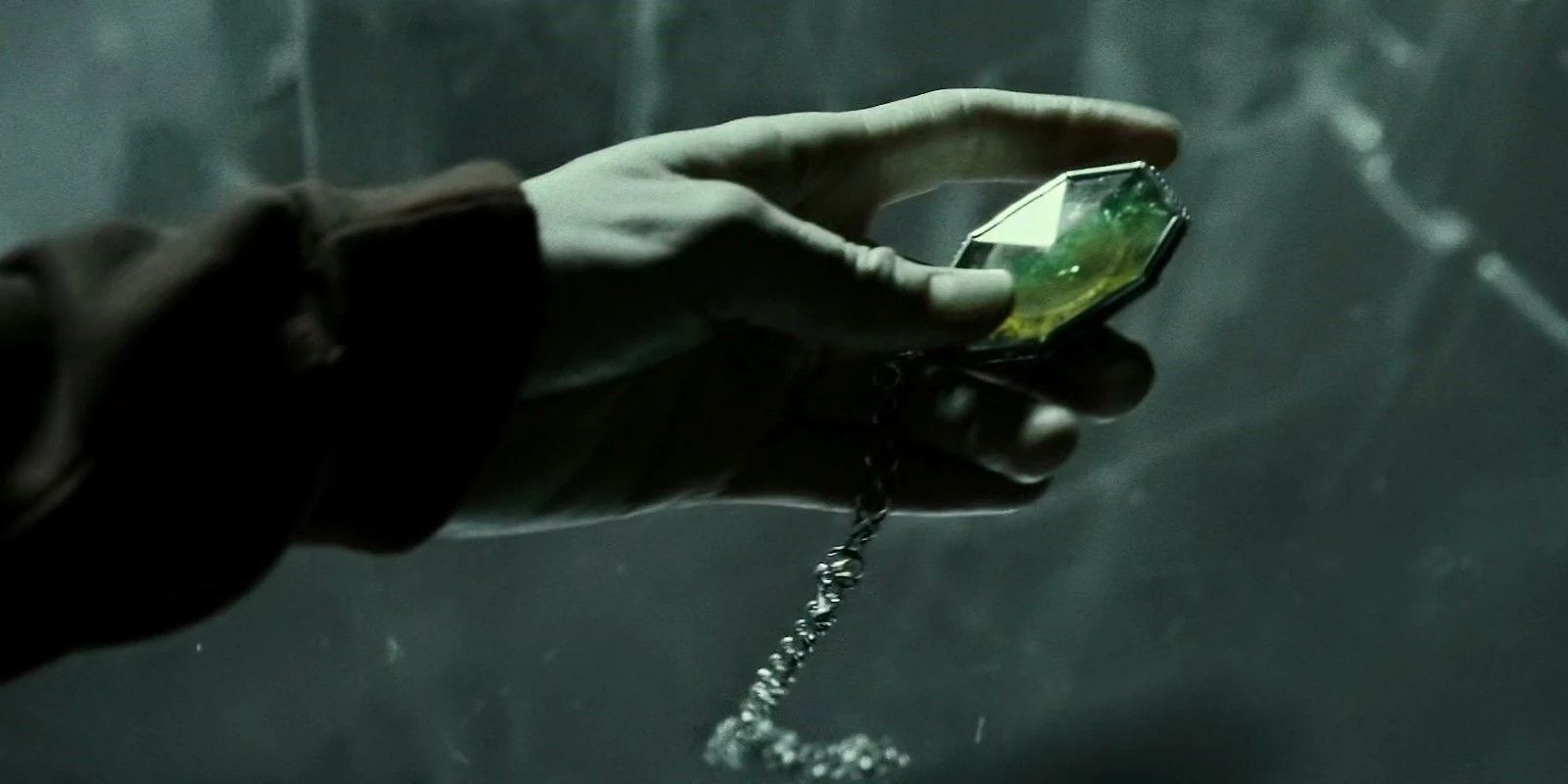 A mão estendida está segurando o medalhão de Slytherin em Harry Potter 