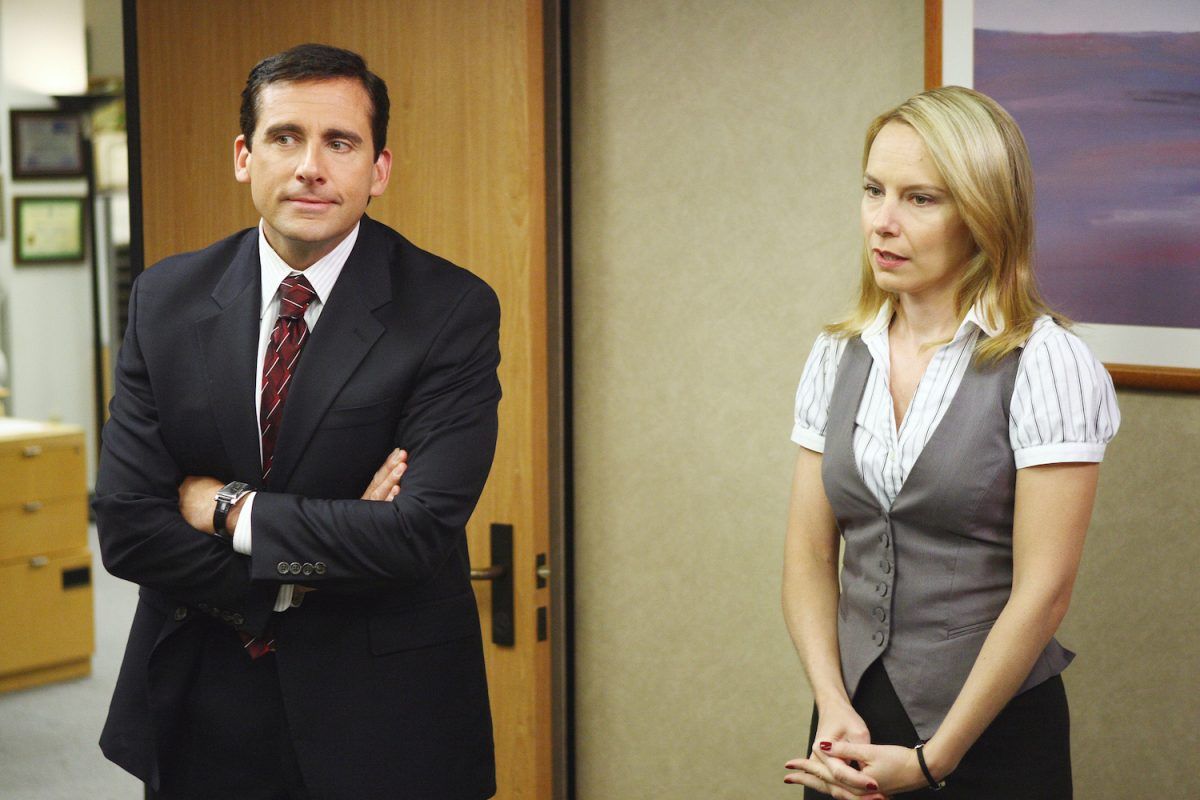 Steve Carrell, arms folded, and Amy Ryan as Holly standing beside him, hands clasped in front of her, in a scene from The Office.