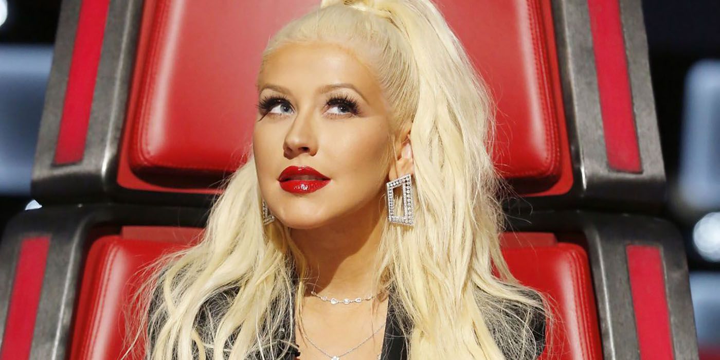 A close-up of Christina Aguilera in her chair on The Voice, eyes looking up, pensive.
