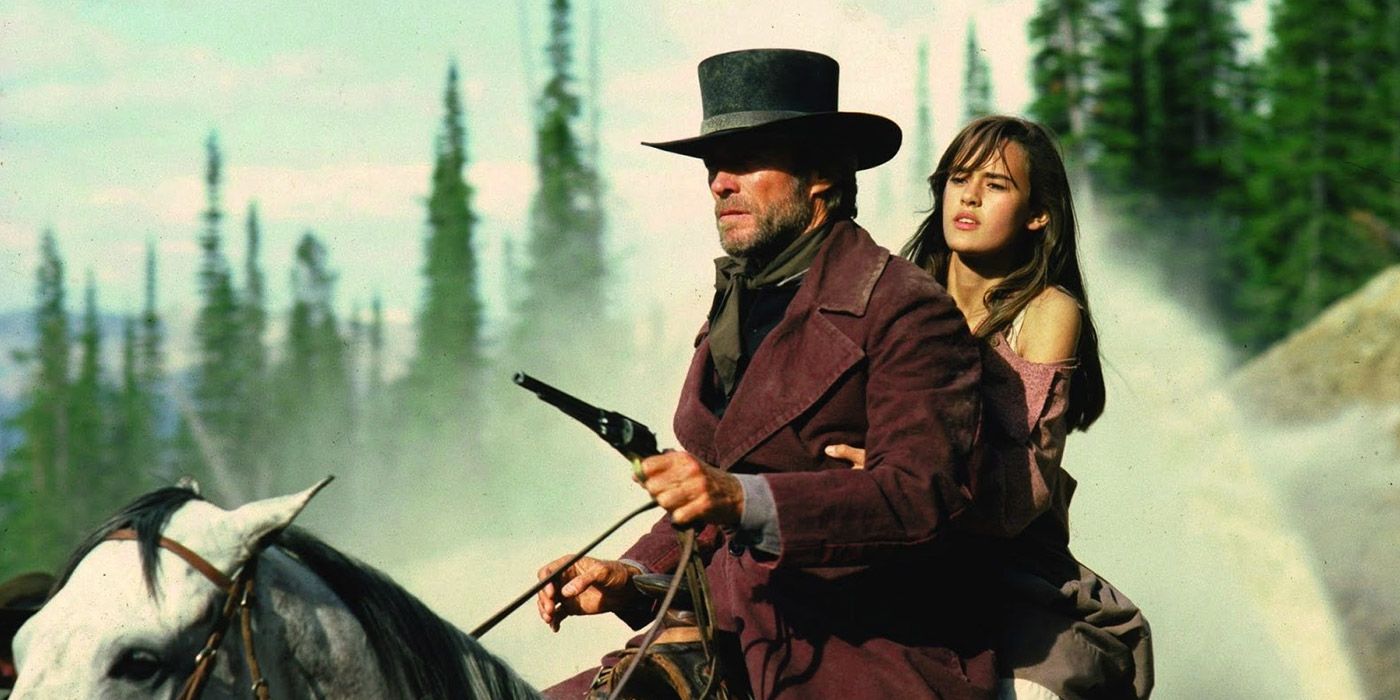 Clint Eastwood as the Preacher on horseback holding a gun with Sydney Penny's Megan in Pale Rider