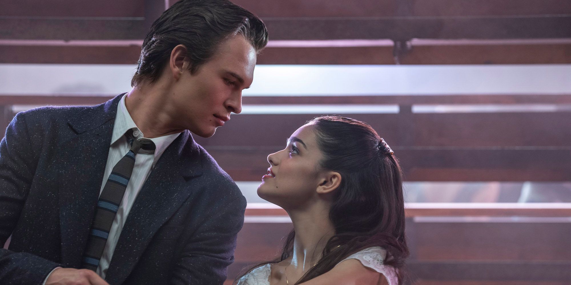 Ansel Elgort and Rachel Zegler look at each other behind the bleachers in West Side Story
