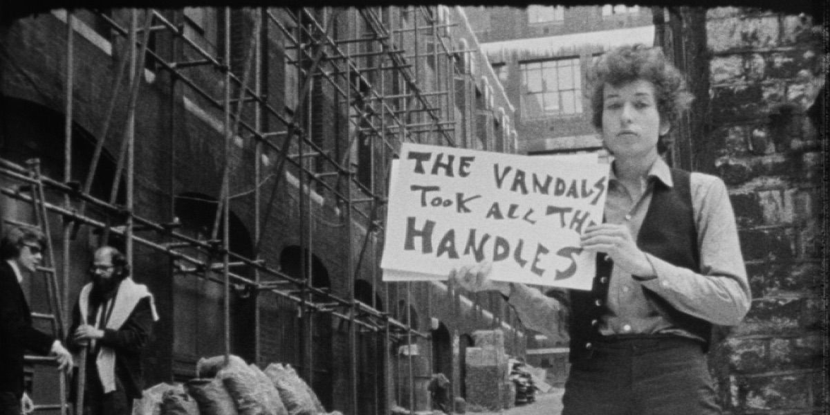 Bob Dylan holds a sign while filming the music video for Subterranean Homesick Blues from Don't Look Back