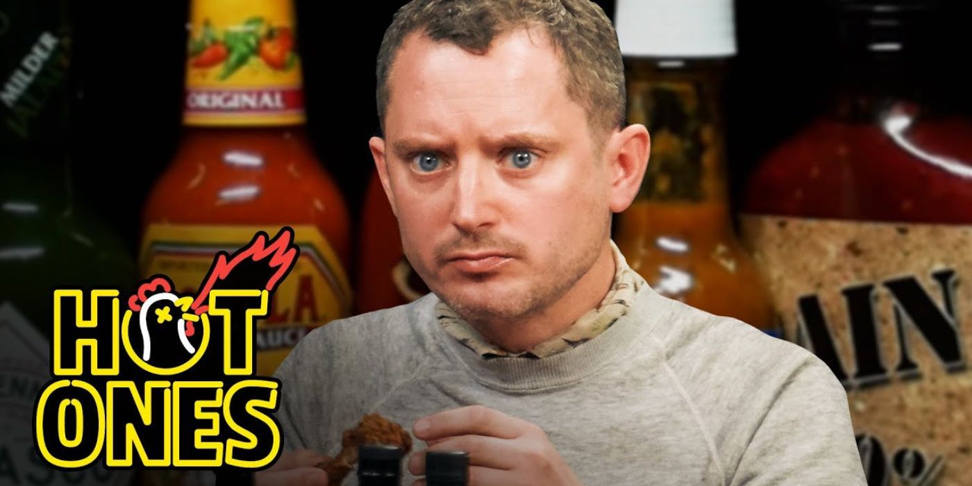 Elijah Wood holds a chicken wing on Hot Ones