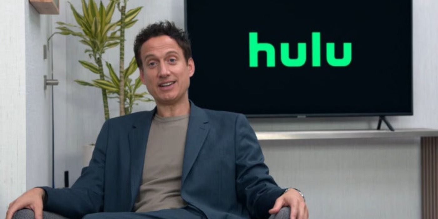Elon Gold sits in front of the Hulu logo in Curb Your Enthusiasm