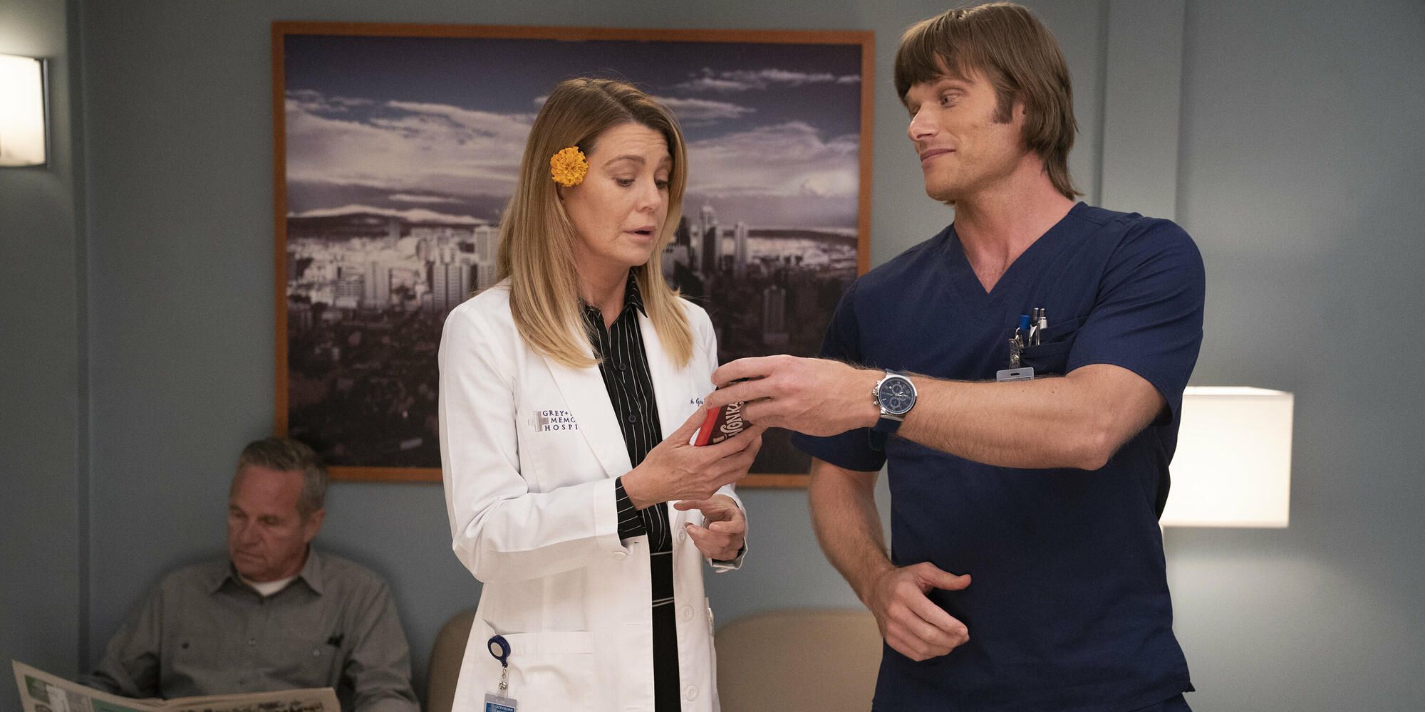 Meredith looks at her phone as another character looks on in Grey&rsquo;s Anatomy.