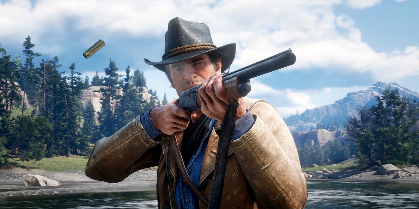 Red Dead Redemption 2's Arthur Morgan stands next to a river in the mountains, firing a shotgun past the camera, with a shotgun shell casing in midair after being ejected.