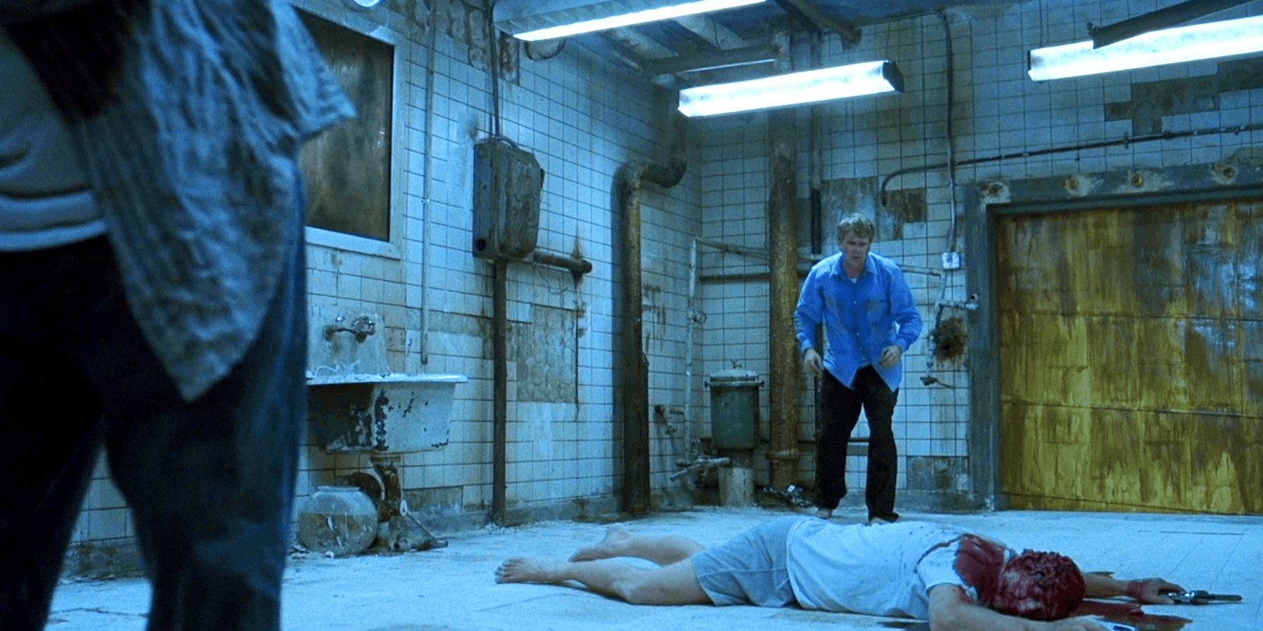 Dois homens olham para um cadáver no chão em Saw