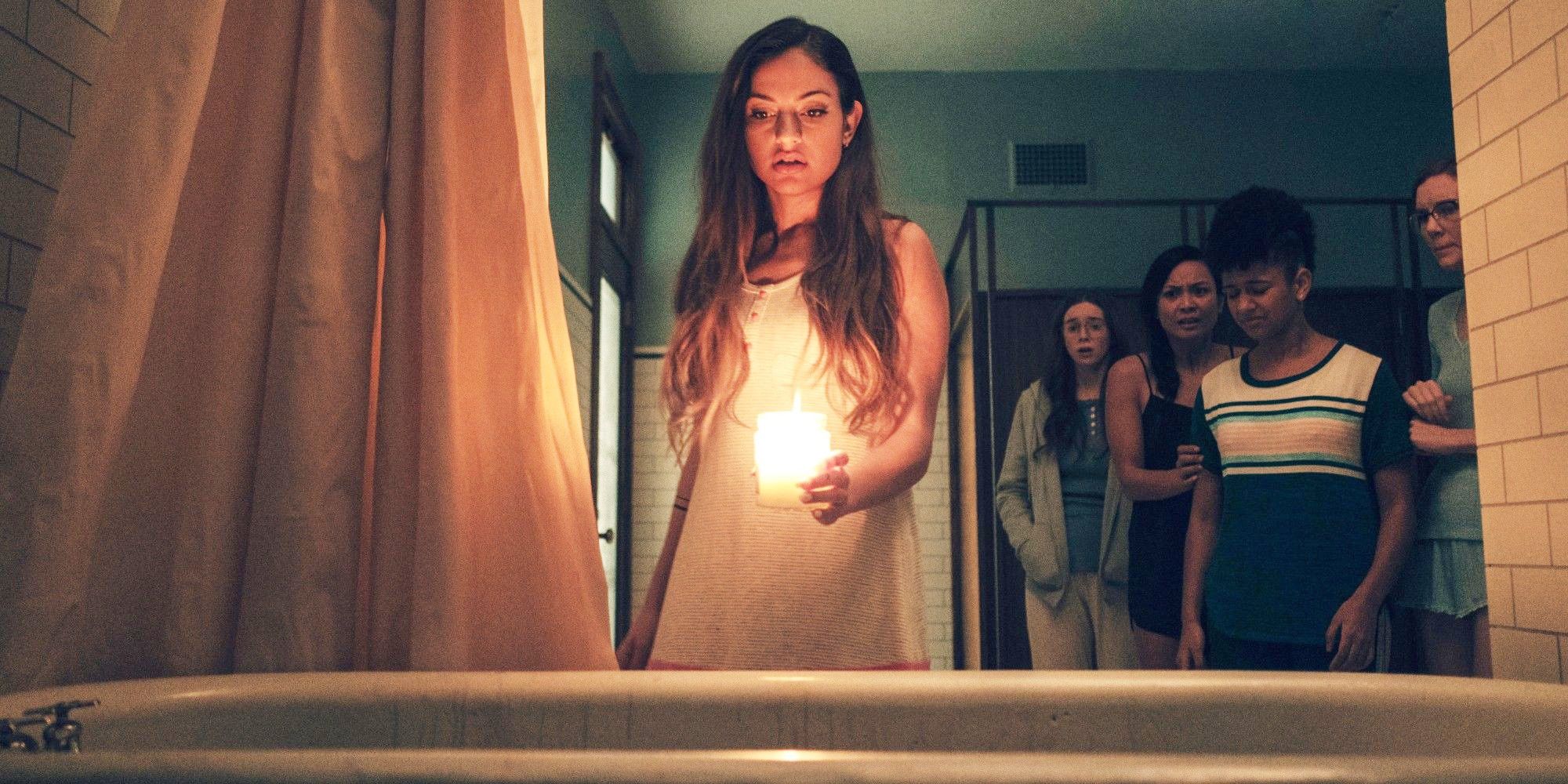 A girl holds candle over a bathtub in Seance.