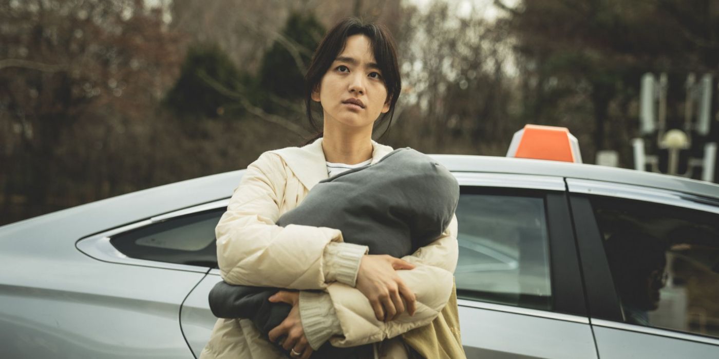 So-hyun holds Toughie in front of a car in Hellbound.