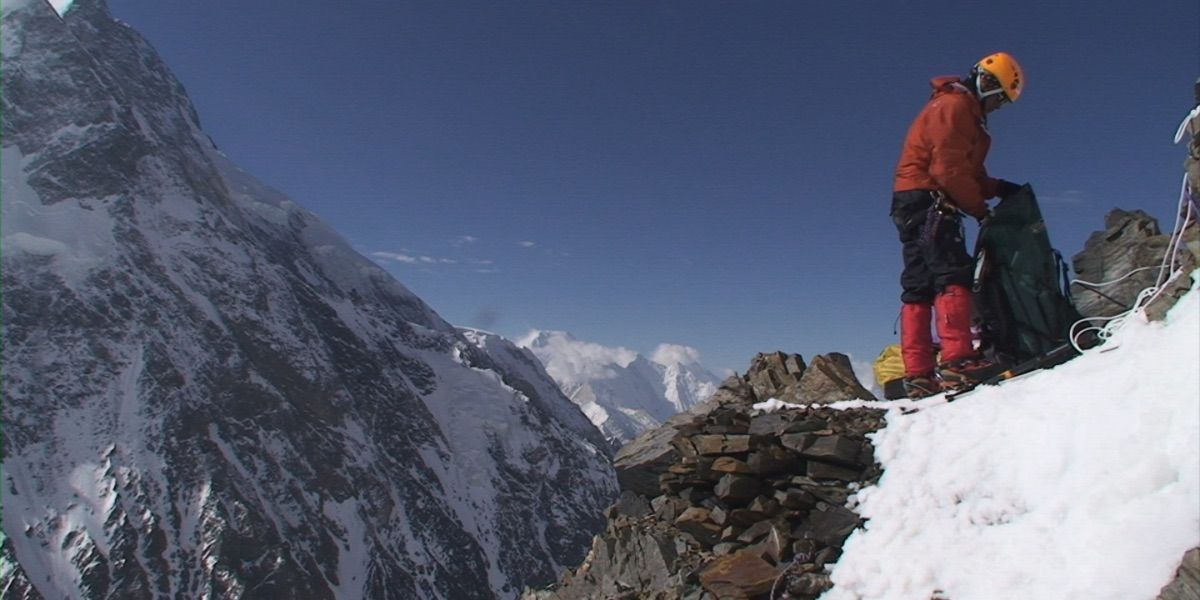 A climber overlooking the mountain landscape in The Summit