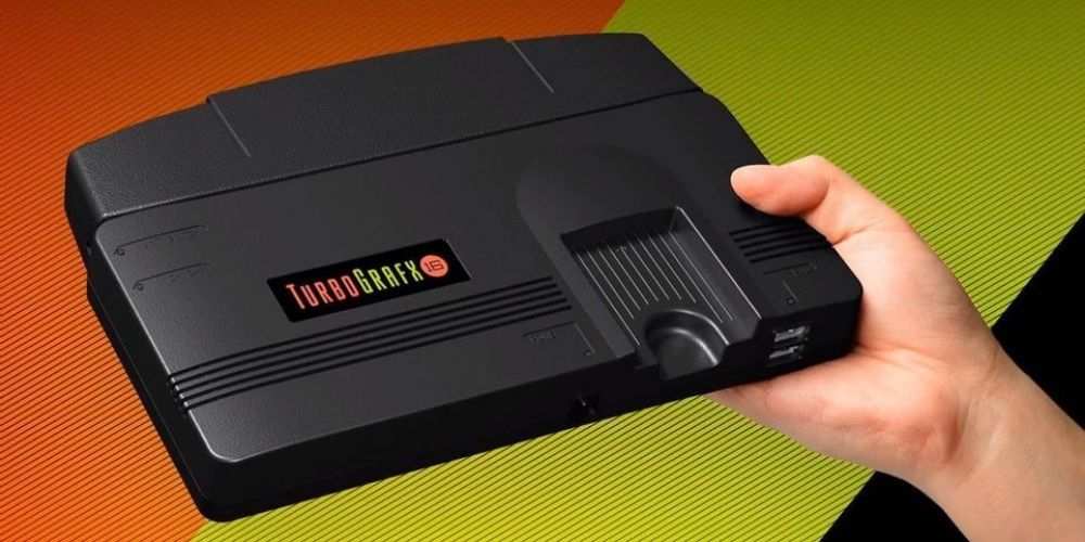 A hand holds a Turbografx mini console