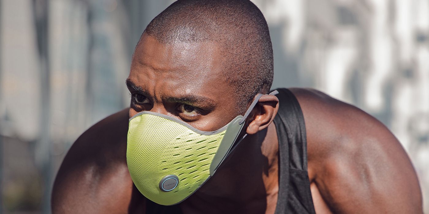 A man wearing a black tank top and the Airpop Active Halo smart mask, bending down.