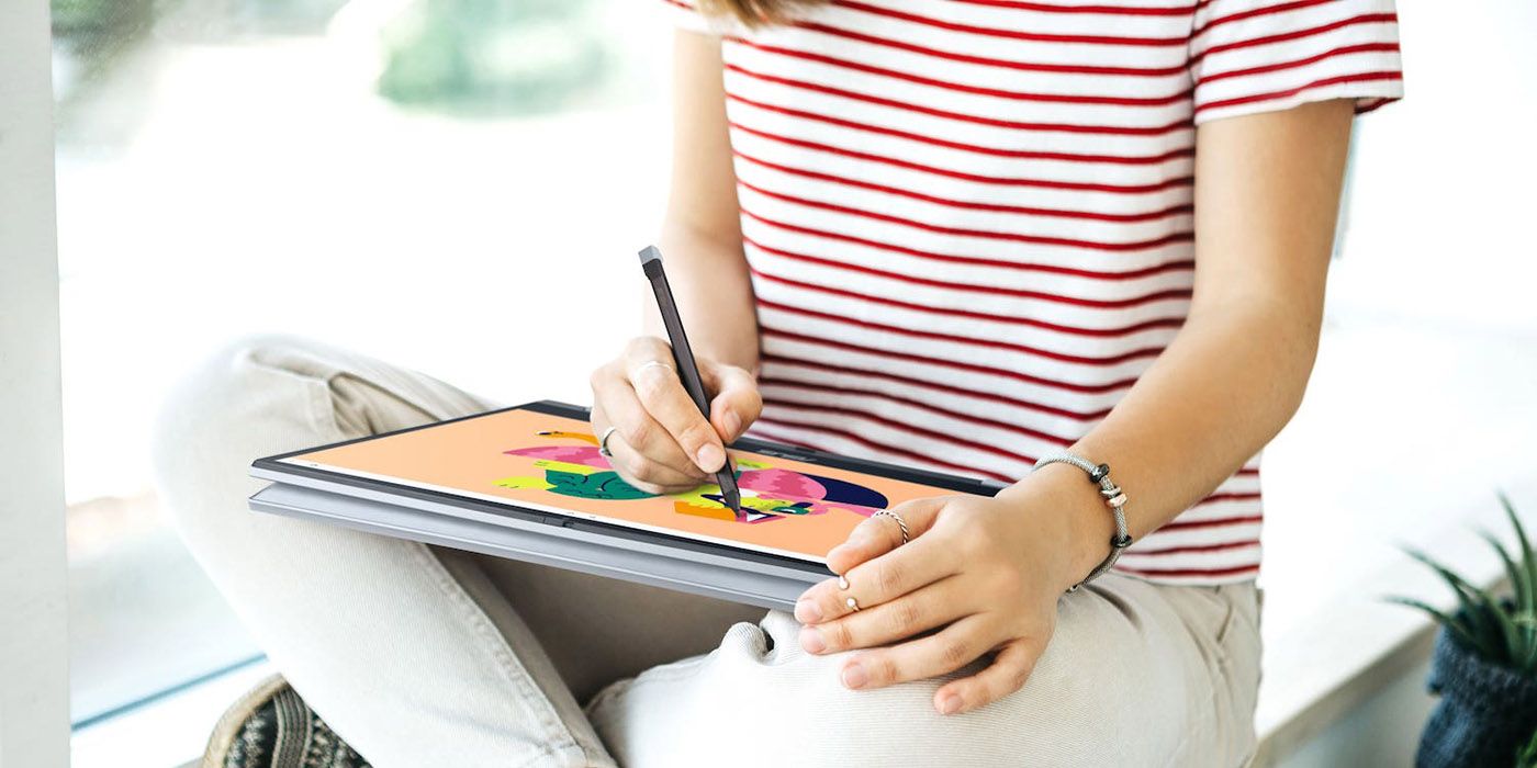 A young girl sitting with an Asus Chromebook Flip CX3 folded over in her lap, drawing on the screen.