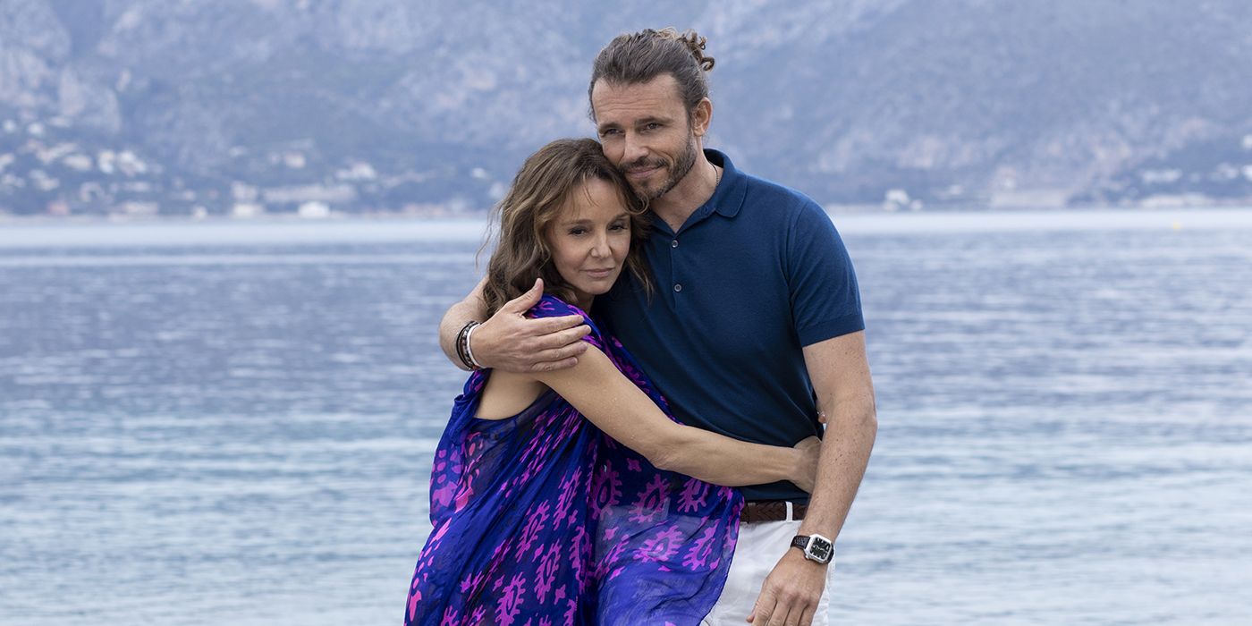 Sylvie and Laurent embracing by the water in a scene from Emily in Paris.