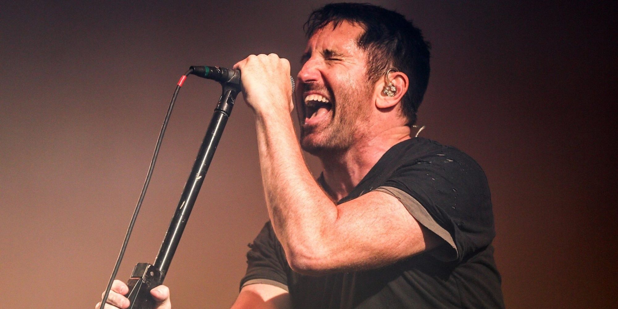 Trent Reznor singing into a microphone on stage