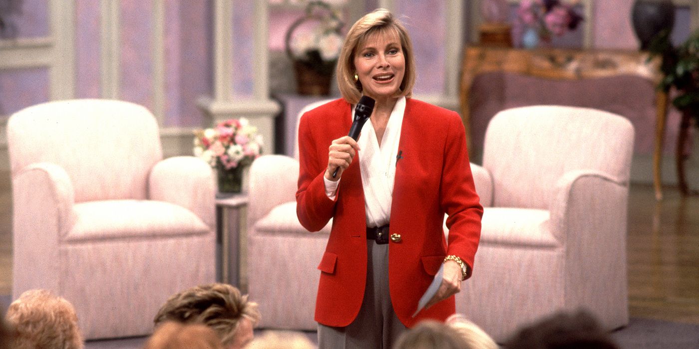 Jenny Jones in a red suit standing in front of her audience.
