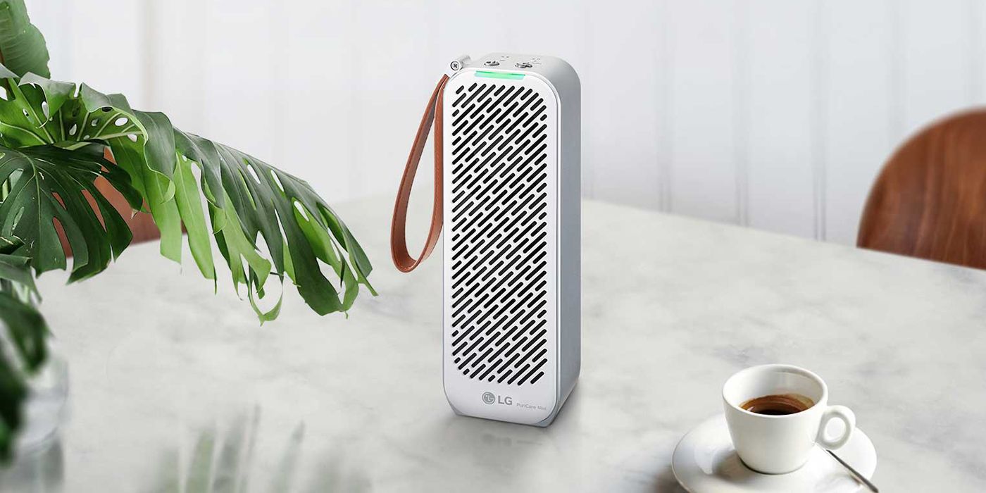 LG Puricare mini portable air purifier sitting on a counter beside a cup of coffee.
