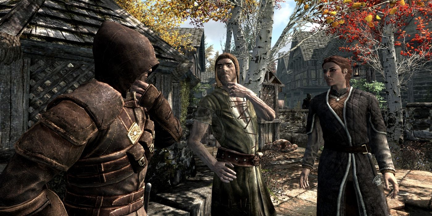 A hooded Skyrim character talking to two NPCs in the streets of Riften.