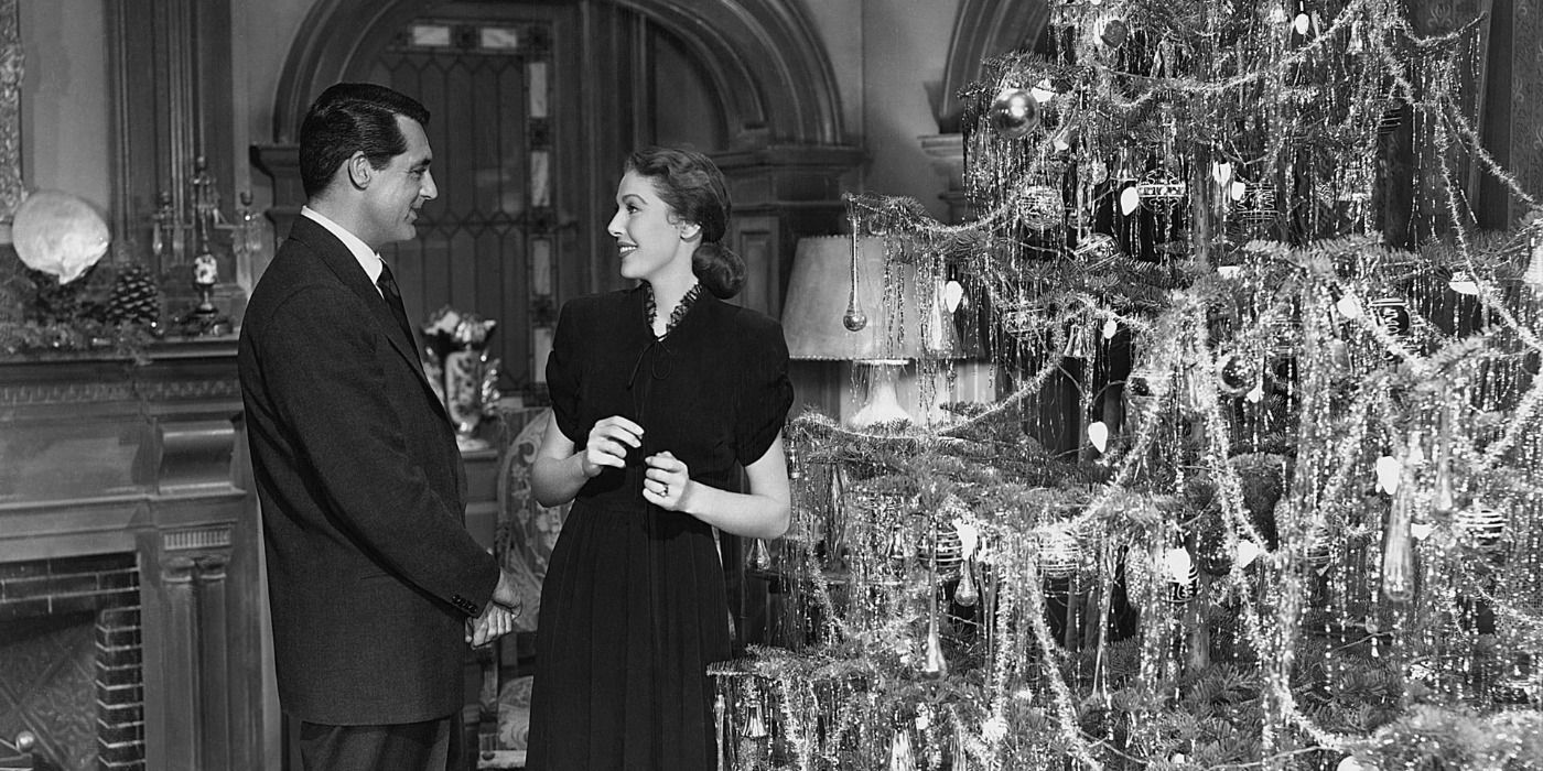 Cary Grant and Loretta young stand next to a Christmas tree in The Bishop's Wife
