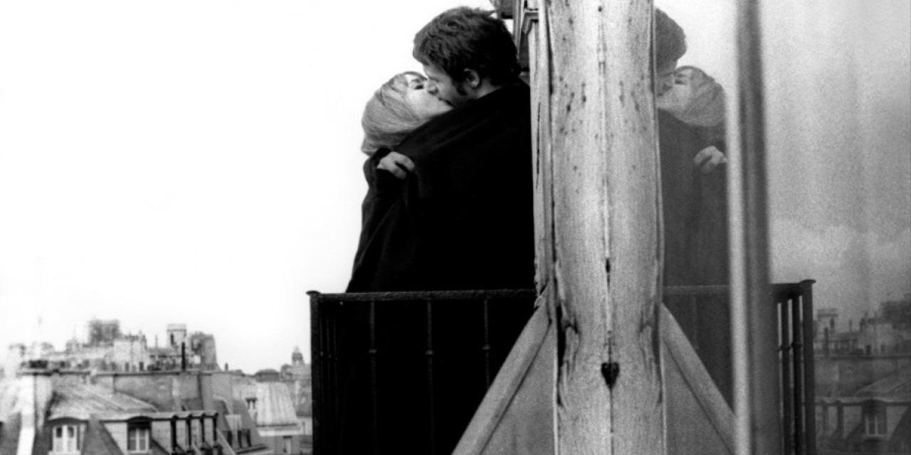 A man and a woman kiss on a balcony in L'amour fou