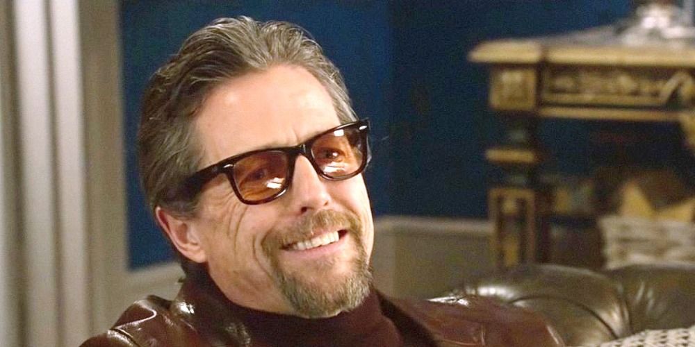 A smiling Hugh Grant in The Gentleman with sunglasses on