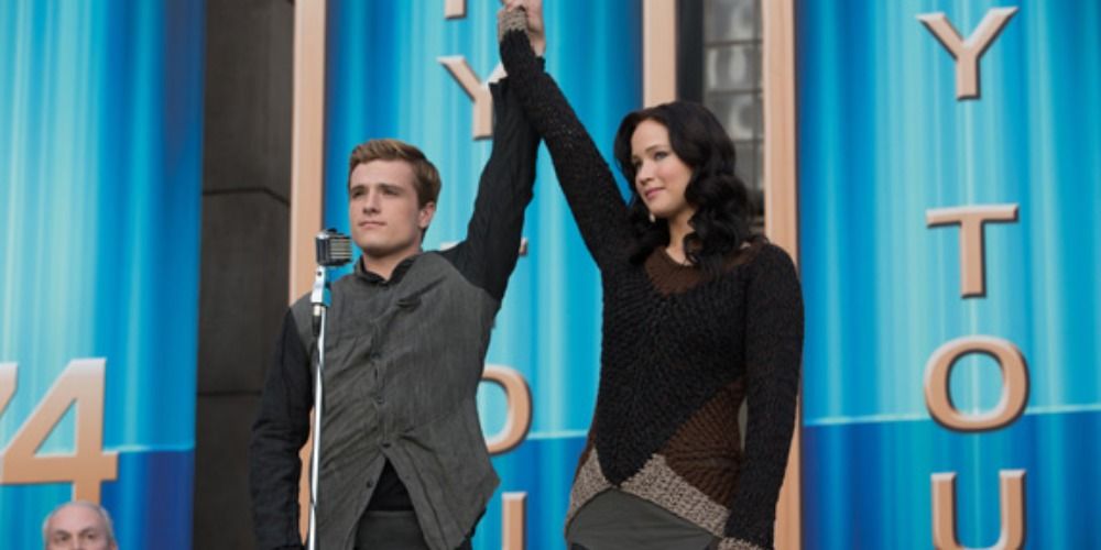 An image of Peeta and Katniss holding their hands up in Catching Fire