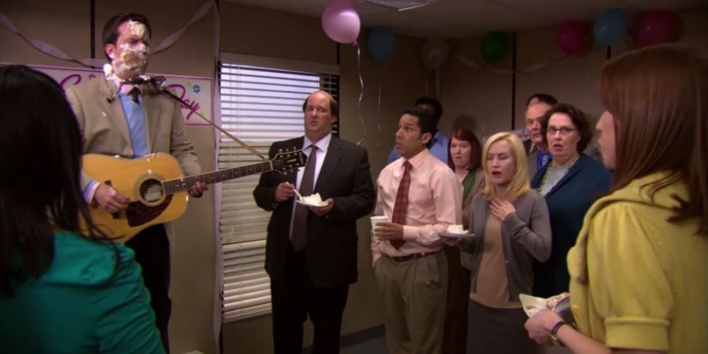 An image with Andy playing a guitar with cake on his face in The Office