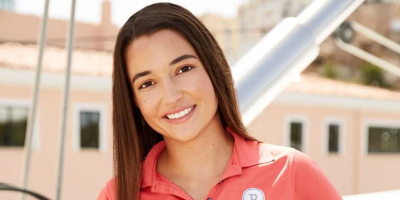 Ashley Marti Below Deck Sailing Yacht smiles, wearing a red yacht uniform closeup