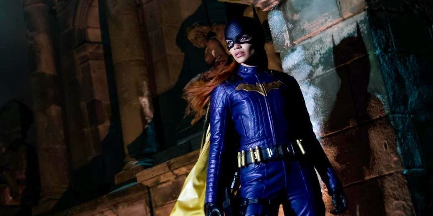 Leslie Grace em pé e olhando de lado usando o cotsume da Batgirl