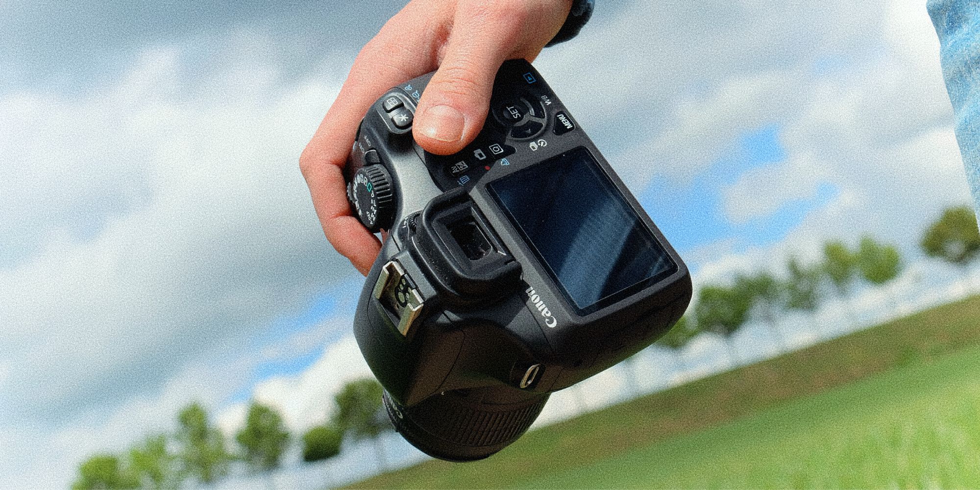 CLOSE UP OF A PERSON HOLDING A DSLR