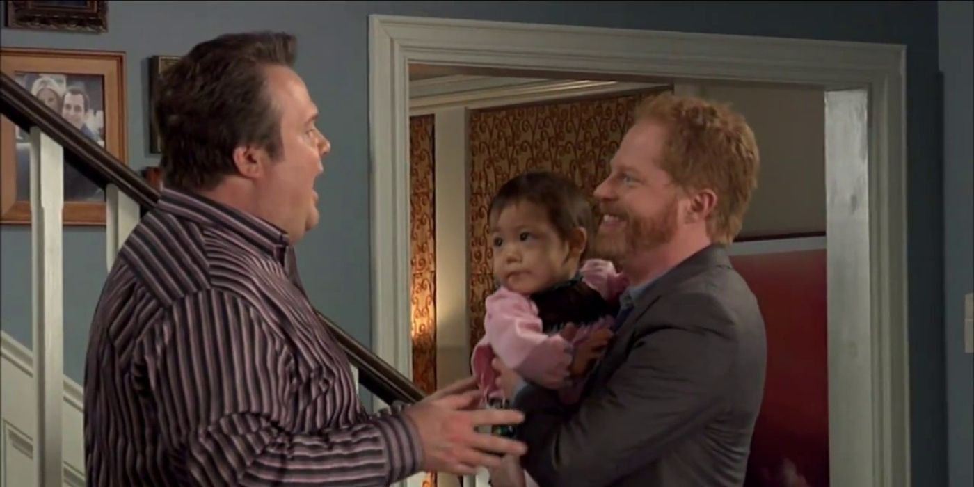 Cam and Mitchell talking while holding Lily on Modern Family